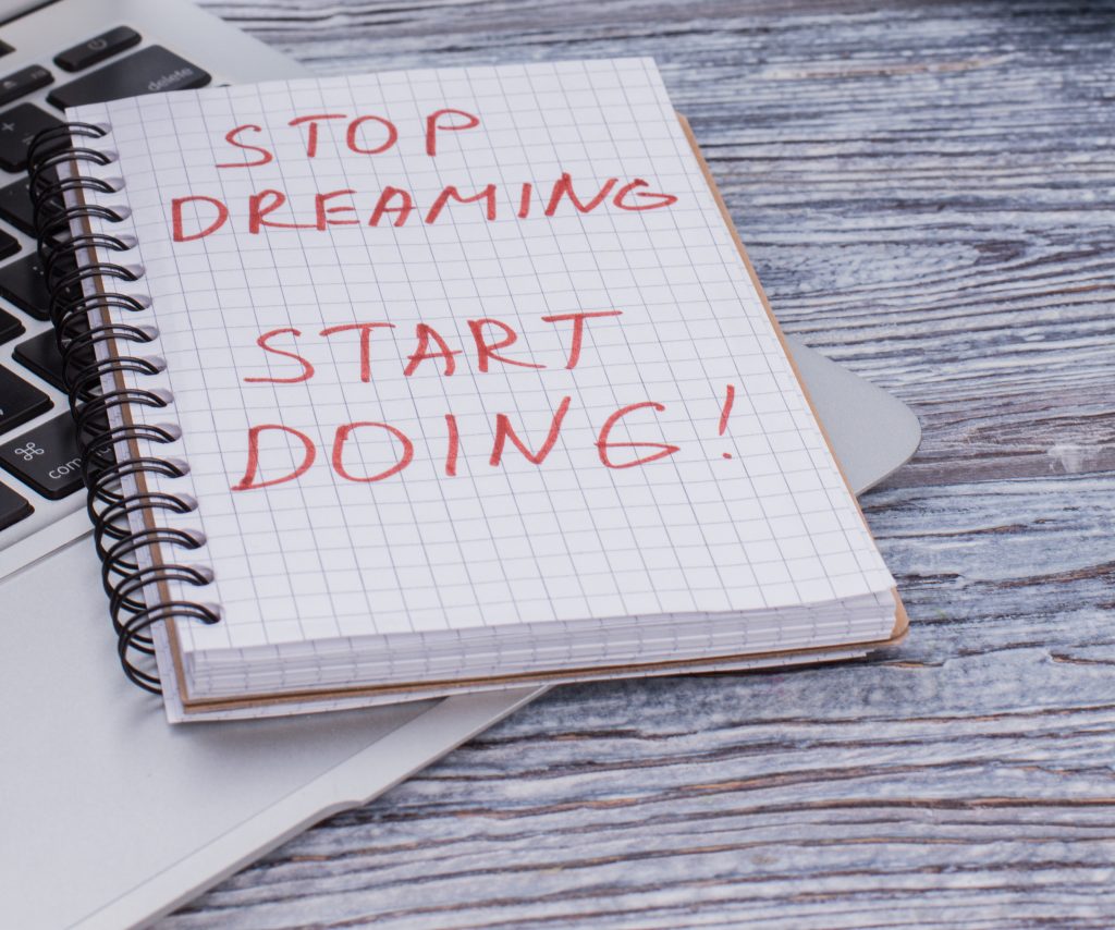 "Stop dreaming start doing" geschrieben auf einem Block
