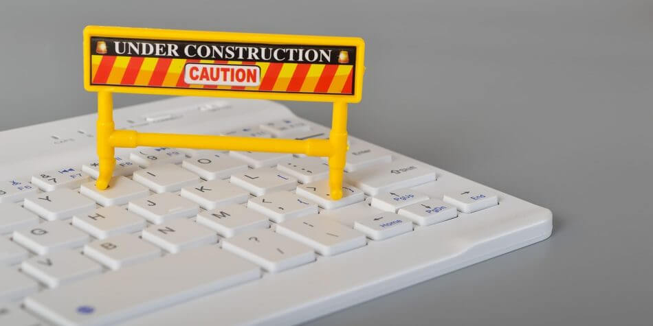 Website Wartung. Miniatur Schild mit "Im Umbau. Vorsicht" als Schriftzug steht auf Tastatur.