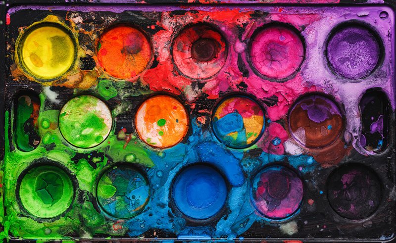 Ein benutzter Aquarellkasten mit Komplementärfarben.