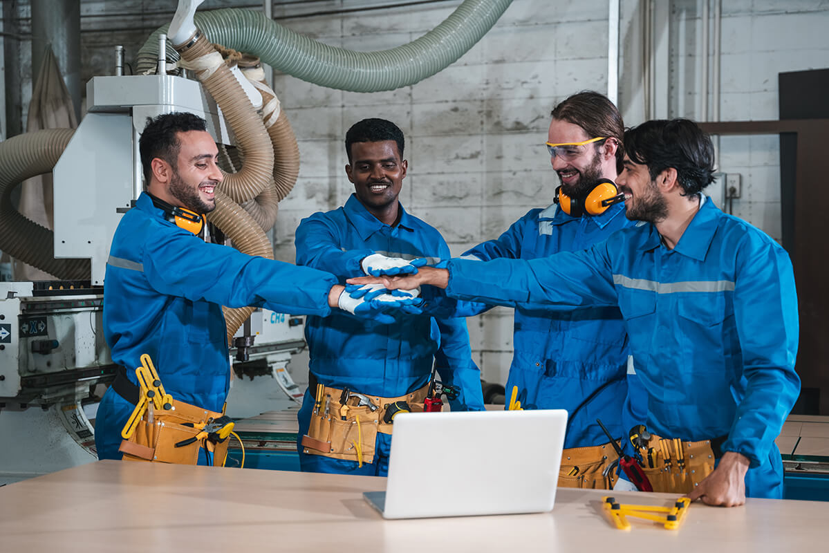 Ein Team von Handwerkern in blauem Overalls vor einem Laptop mit Webdesign für Handwerker